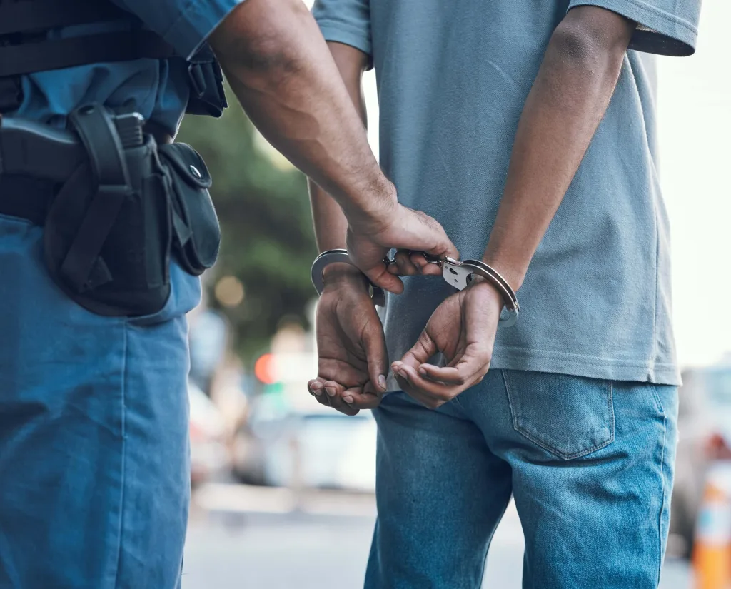 Handcuffs, policeman hands with criminals in the city for justice, crime or corruption.